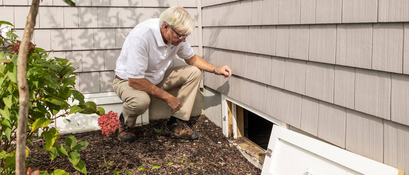 Radon specialist inspecting a crawl-space opening for mitigation planning in Cincinnati
